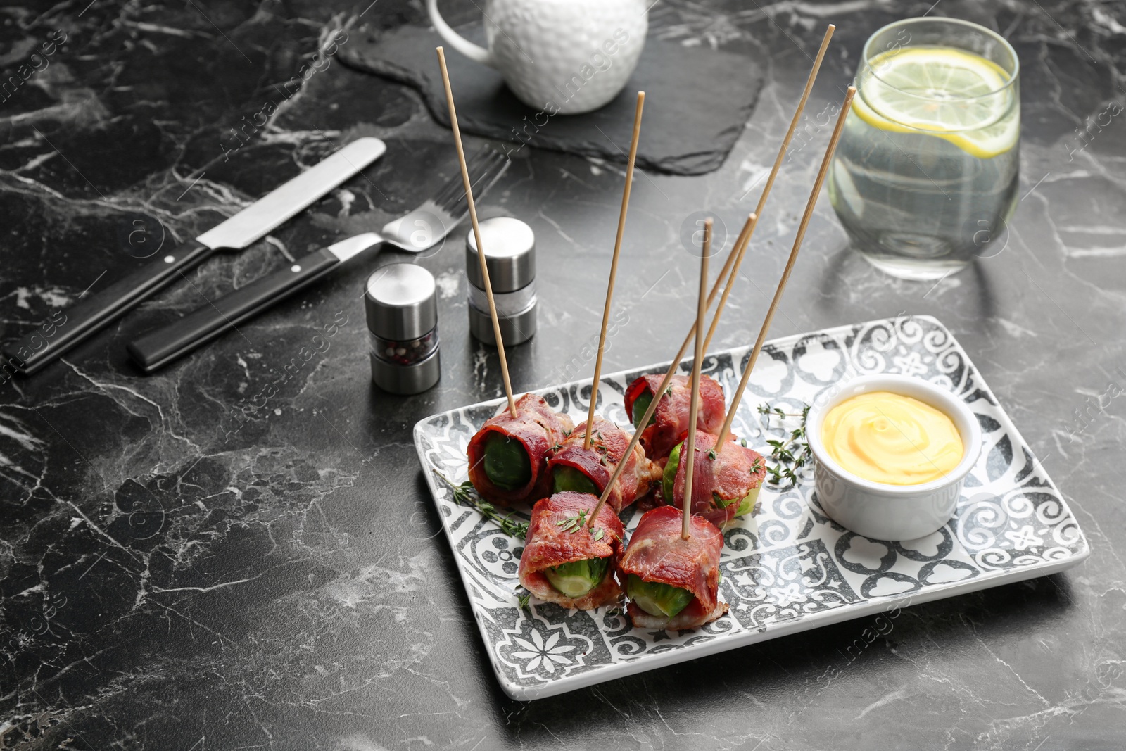 Photo of Plate with Brussels sprouts wrapped in bacon on marble table