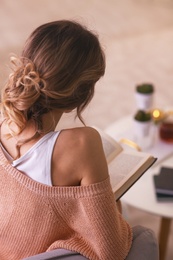 Photo of Woman with book relaxing at home, back view. Cozy atmosphere