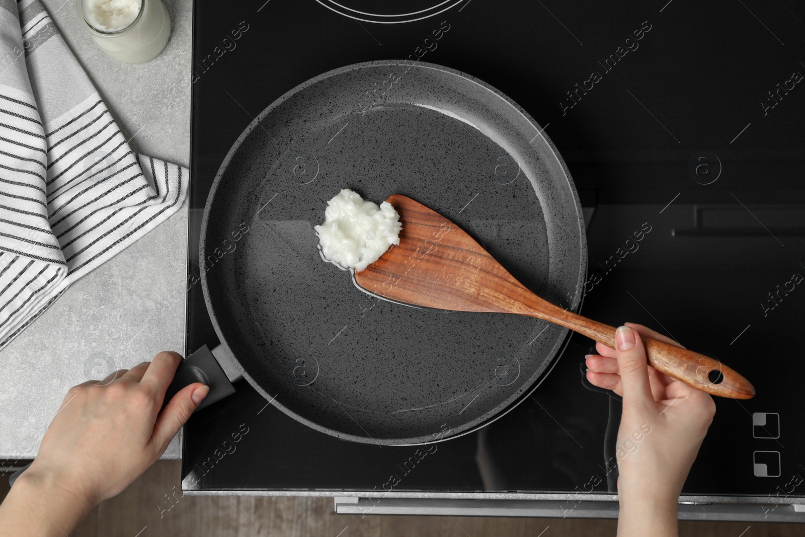 Photo of Woman cooking with coconut oil on induction stove, top view