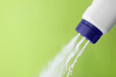 Scattering of baby powder on light green background, closeup. Space for text