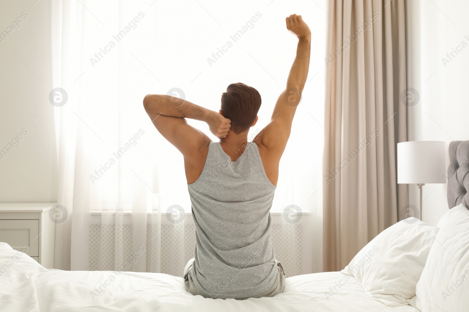 Photo of Man awakening on bed at home. Lazy morning