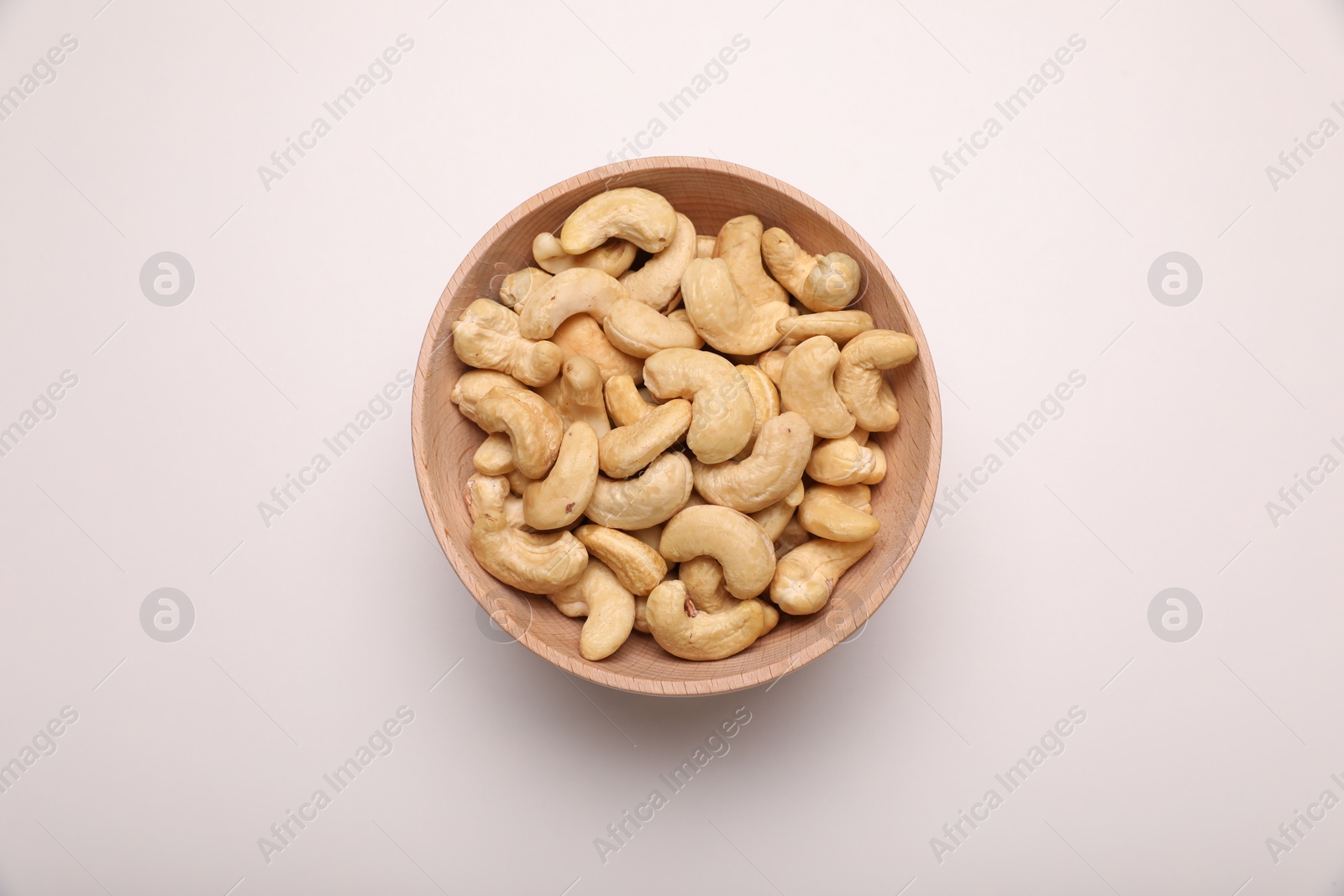 Photo of Bowl with tasty cashew nuts on white background, top view