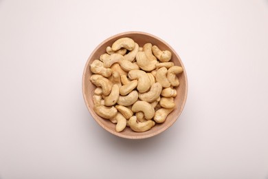 Photo of Bowl with tasty cashew nuts on white background, top view