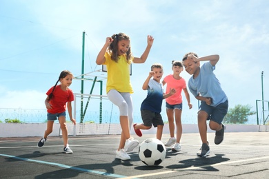 Photo of Cute children playing soccer outdoors on sunny day. Summer camp
