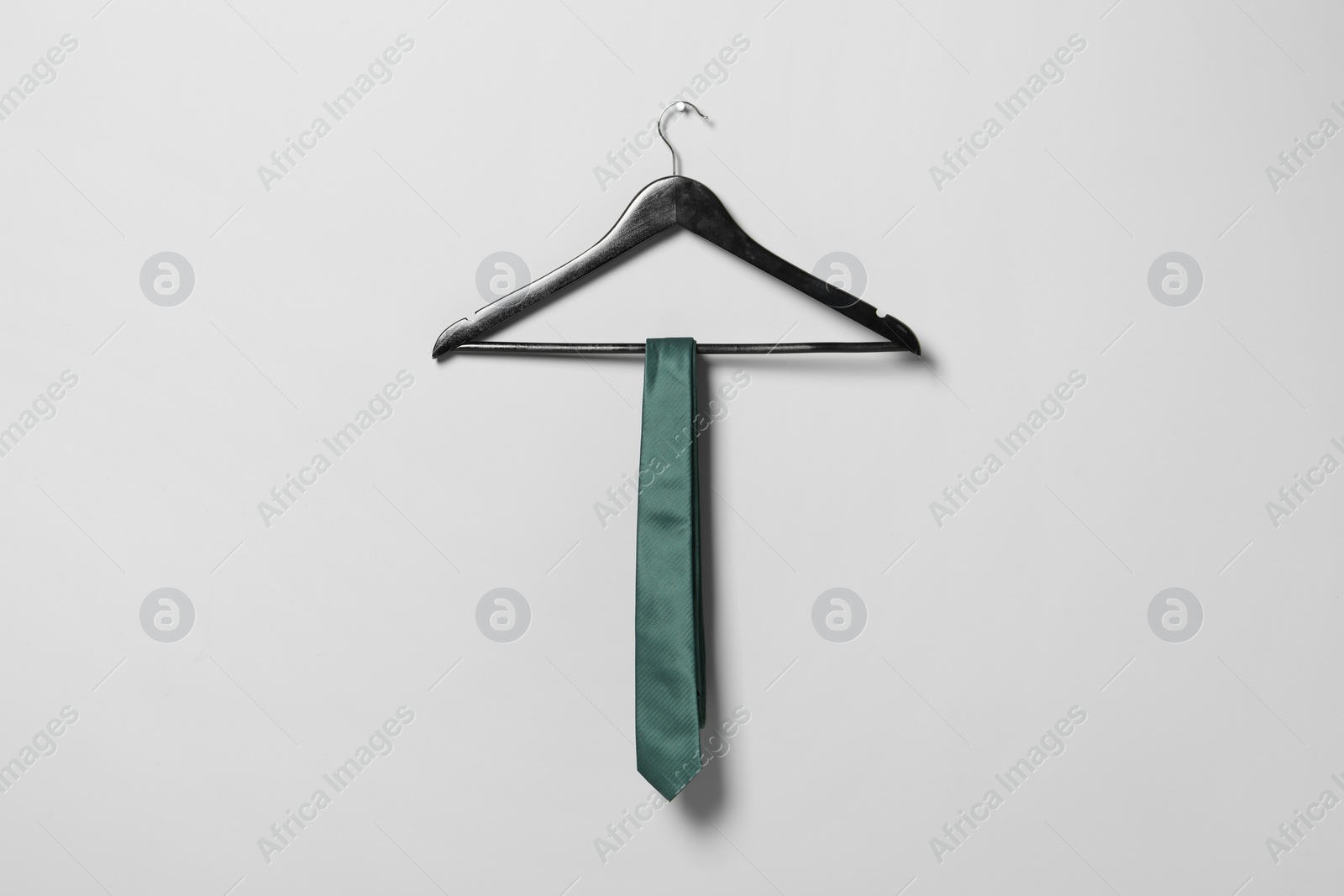 Photo of Hanger with green necktie on light grey wall