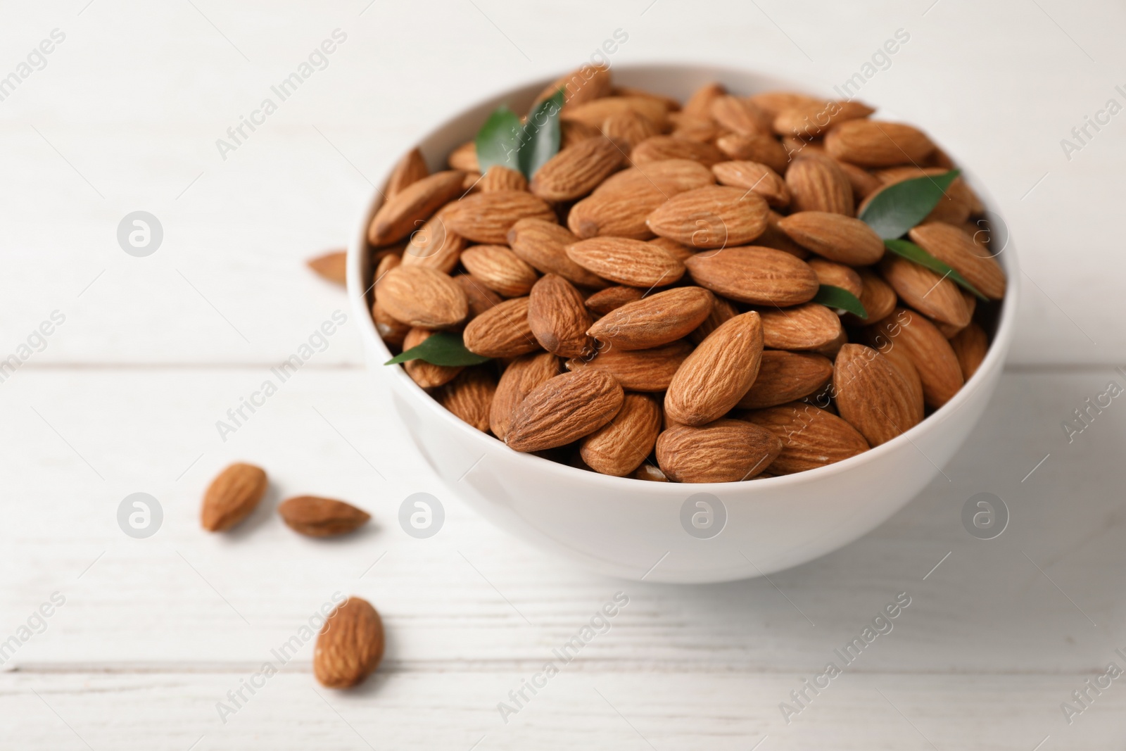 Photo of Tasty organic almond nuts in bowl on table