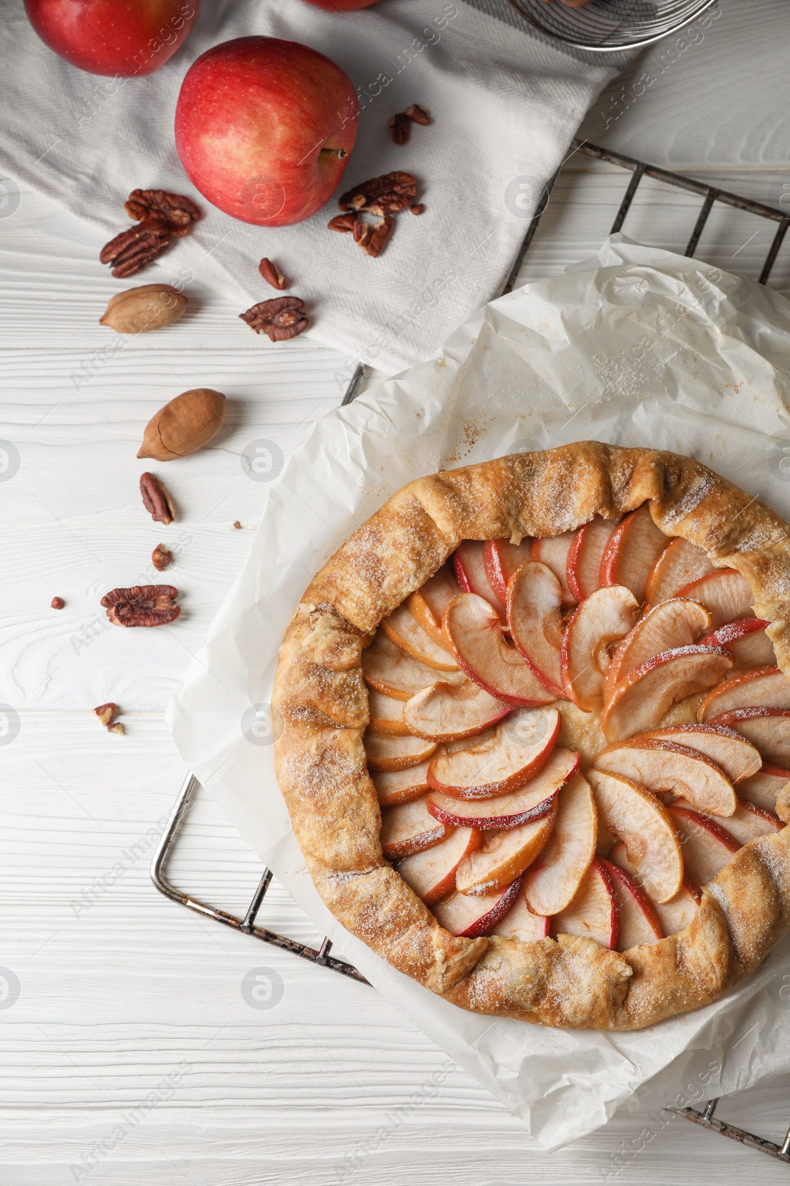 Photo of Delicious apple galette and pecans on white wooden table, flat lay