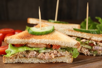 Delicious sandwiches with tuna and vegetables on wooden board, closeup