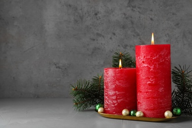 Beautiful Christmas composition with burning red candles on grey background. Space for text