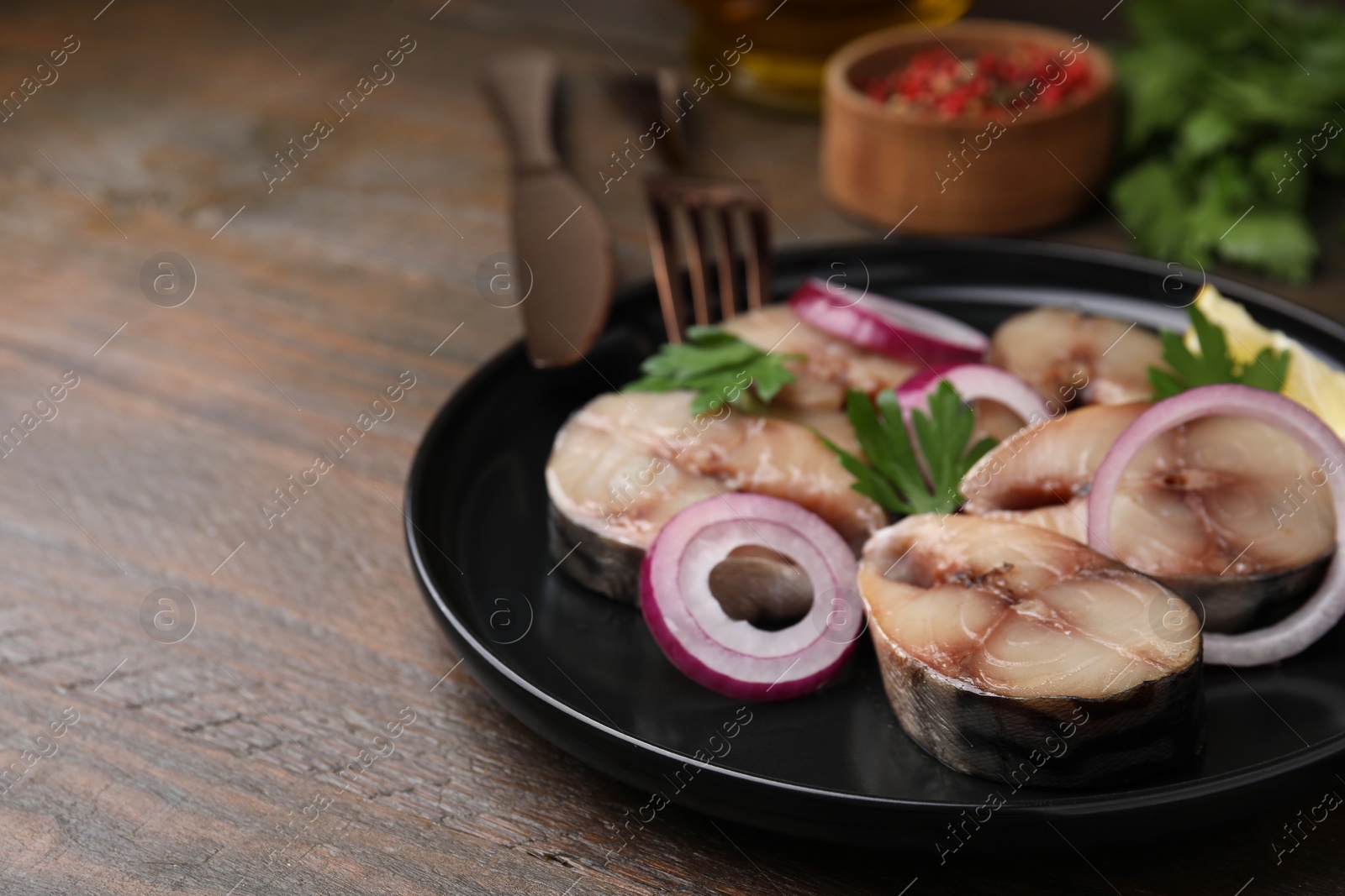 Photo of Slices of tasty salted mackerel, onion rings and parsley on wooden table, closeup. Space for text