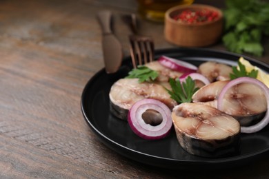 Slices of tasty salted mackerel, onion rings and parsley on wooden table, closeup. Space for text