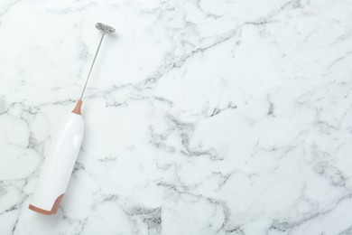 Photo of Milk frother wand on white marble table, top view. Space for text