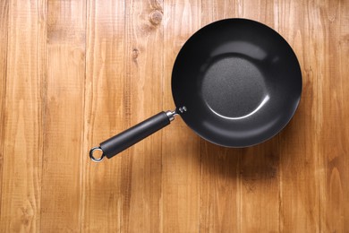 Photo of Empty iron wok on wooden table top view. Chinese cookware