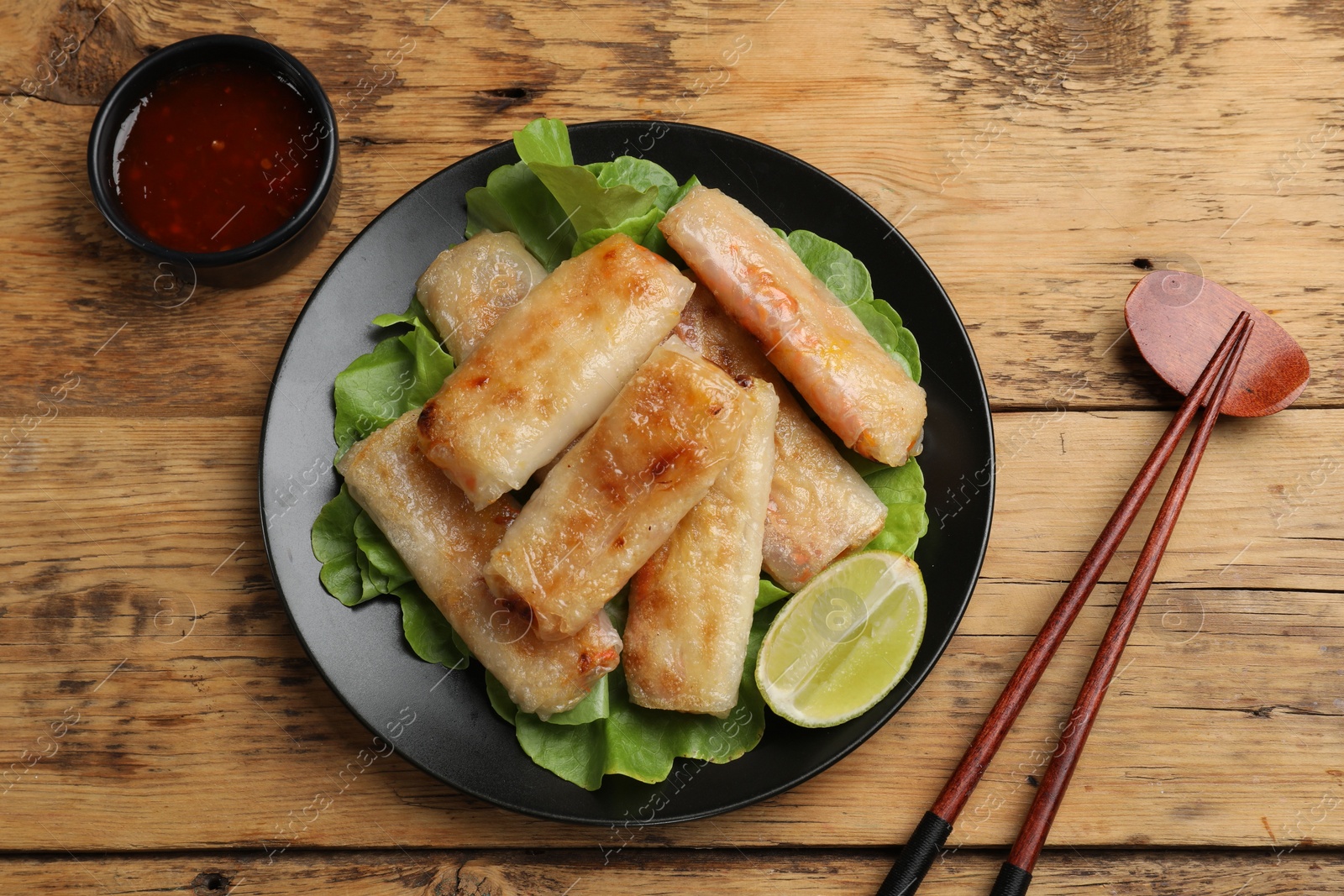 Photo of Tasty fried spring rolls served on wooden table, flat lay