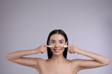 Photo of Woman using silkworm cocoons in skin care routine on light grey background. Space for text