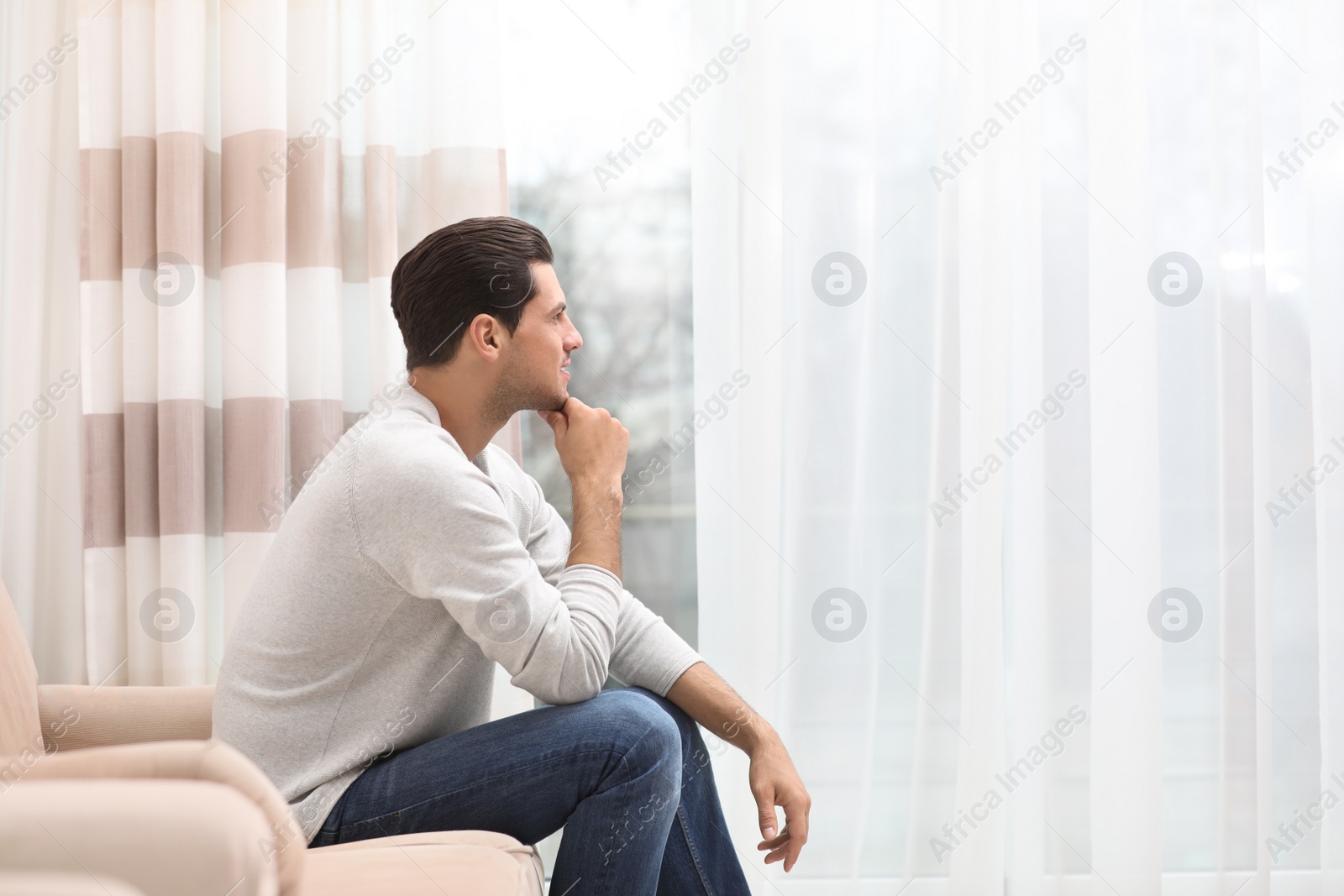 Photo of Handsome man resting on couch near window at home. Space for text