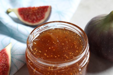 Photo of Jar of tasty sweet jam and fresh figs on table, closeup