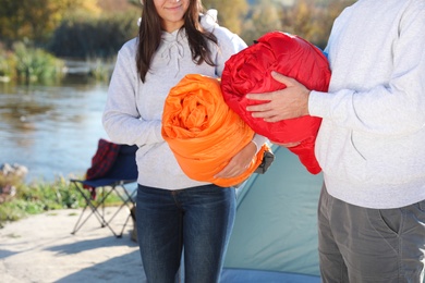 Photo of Young couple with sleeping bags near camping tent outdoors