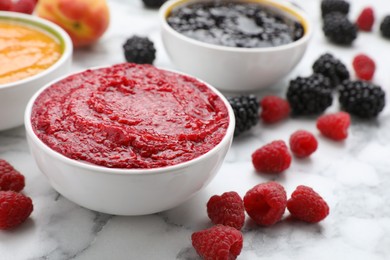 Photo of Different puree in bowls and fresh ingredients on white marble table, closeup