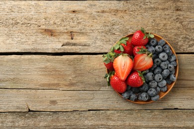 Fresh strawberries and blueberries on old wooden table, top view. Space for text