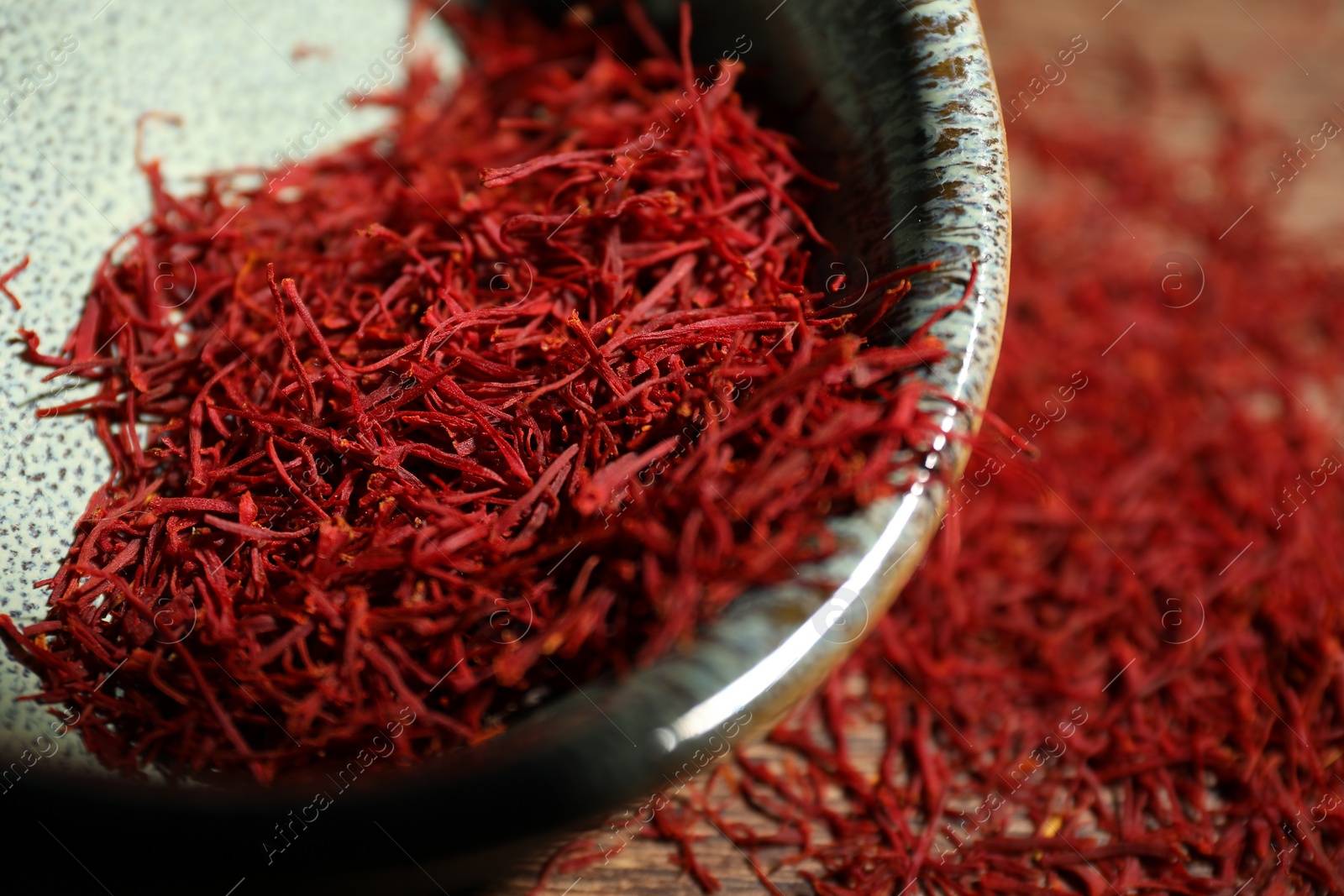 Photo of Aromatic saffron in bowl on table, closeup