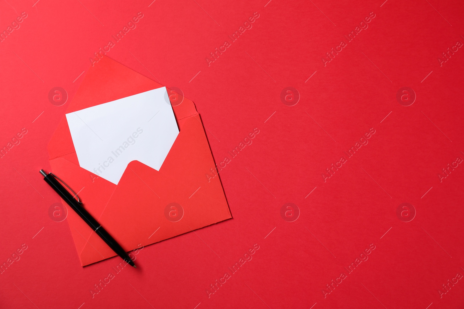 Photo of Blank sheet of paper, letter envelope and pen on red background, top view. Space for text