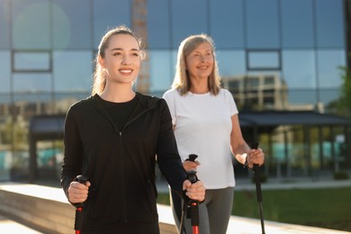 Happy women practicing Nordic walking with poles outdoors on sunny day