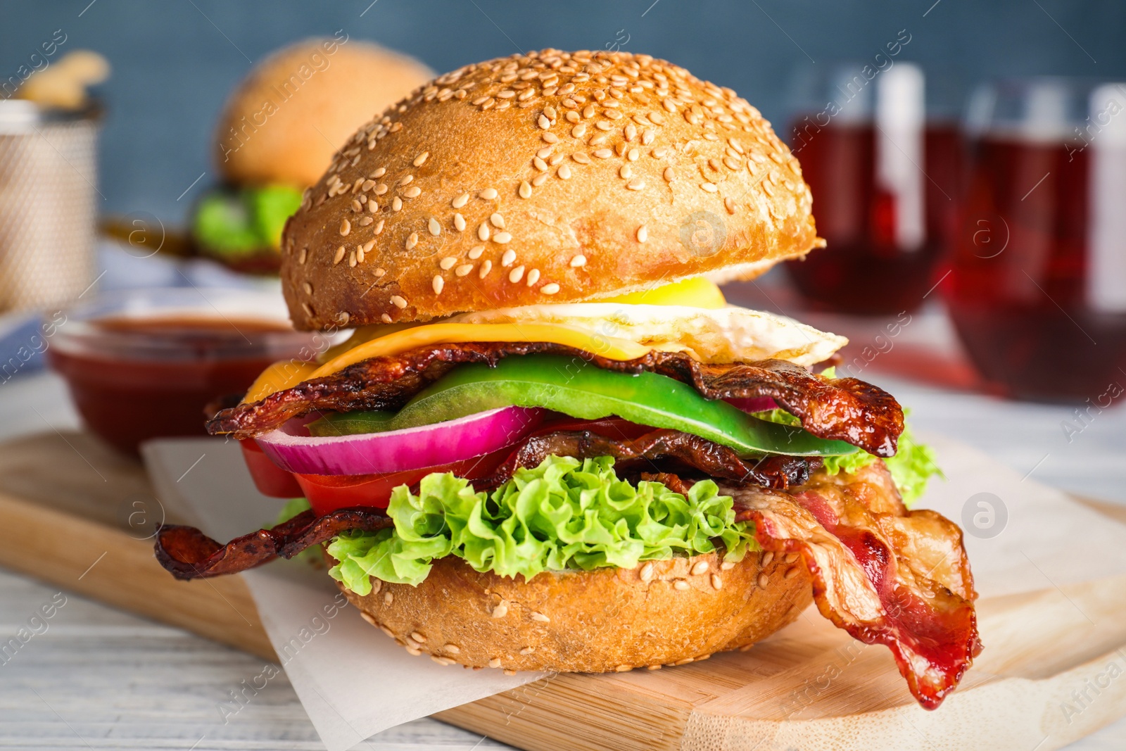 Photo of Fresh juicy bacon burger on white wooden table