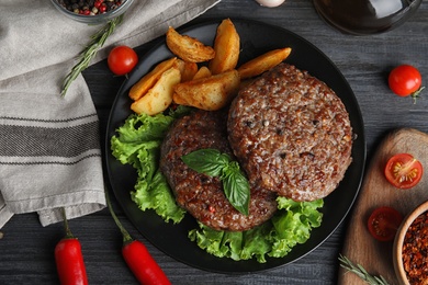 Photo of Flat lay composition with grilled meat cutlets for burger on black wooden table
