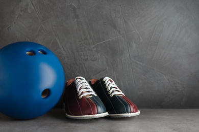 Photo of Bowling shoes and ball on grey stone table. Space for text