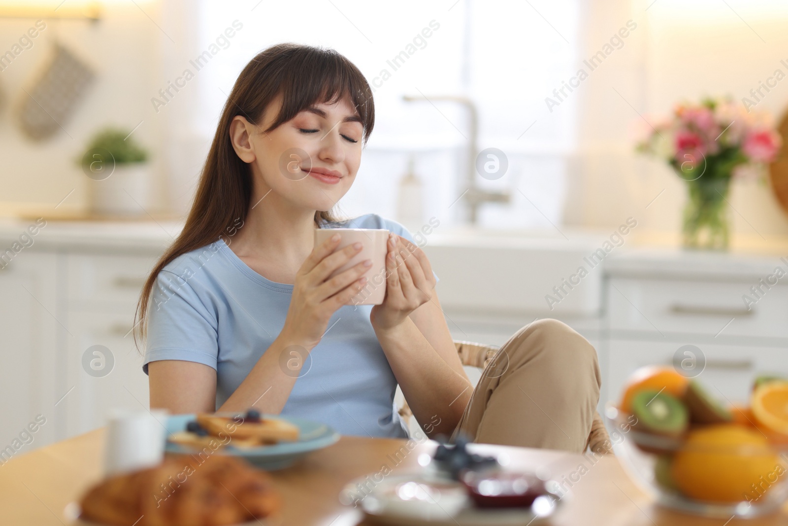 Photo of Beautiful woman drinking coffee at breakfast indoors