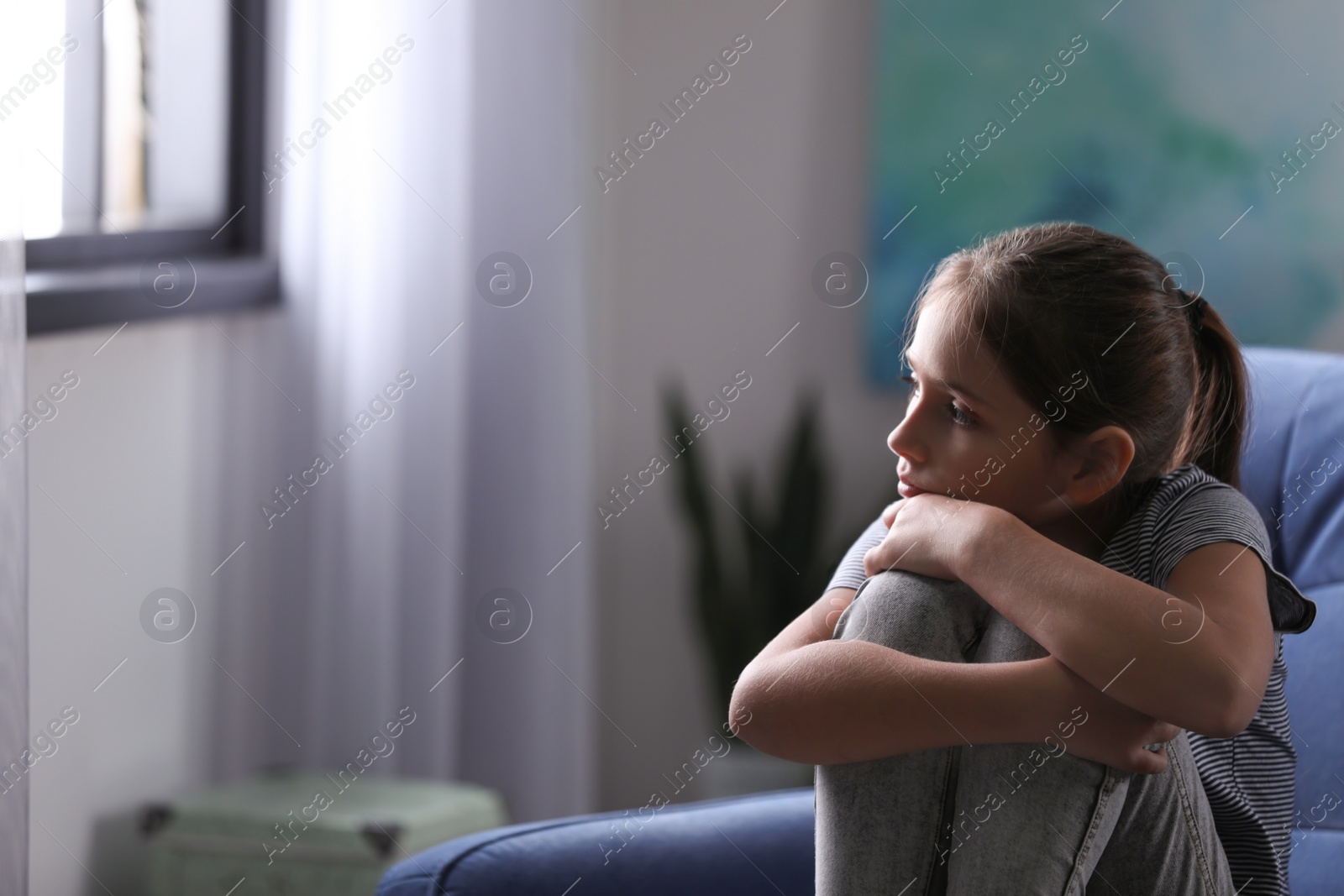 Photo of Depressed preteen girl sitting in armchair at home