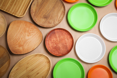 Photo of Many plastic and wooden plates on beige background, flat lay. Recycling concept