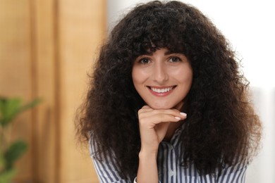 Photo of Portrait of beautiful woman with curly hair indoors. Attractive lady smiling and looking into camera. Space for text