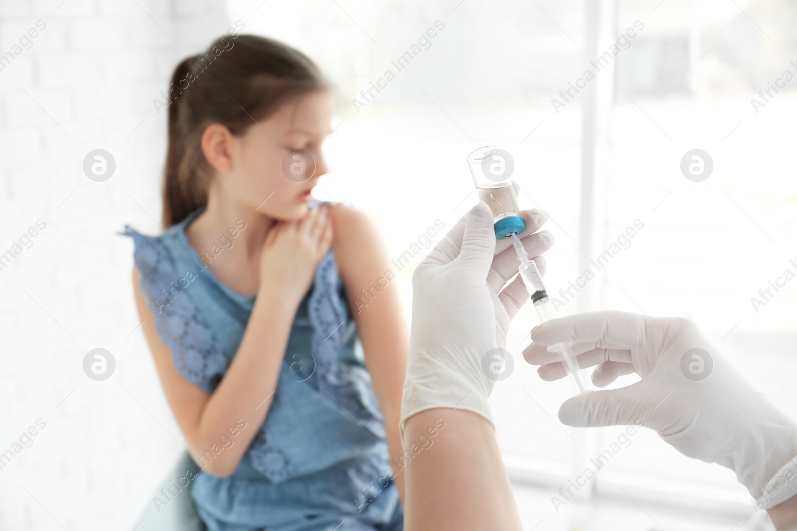 Photo of Doctor filling syringe with medicine and child on background. Vaccination day