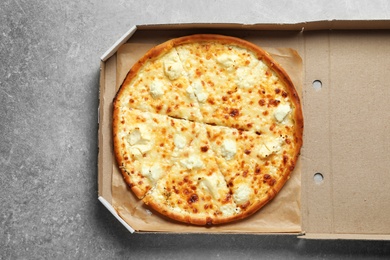 Photo of Carton box with delicious pizza on grey background, top view