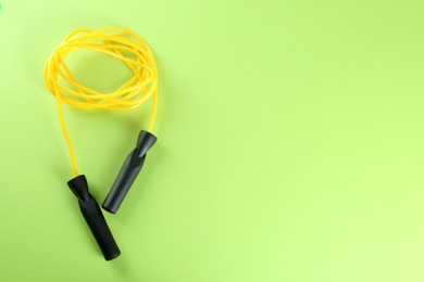 Photo of Skipping rope on green background, top view. Space for text
