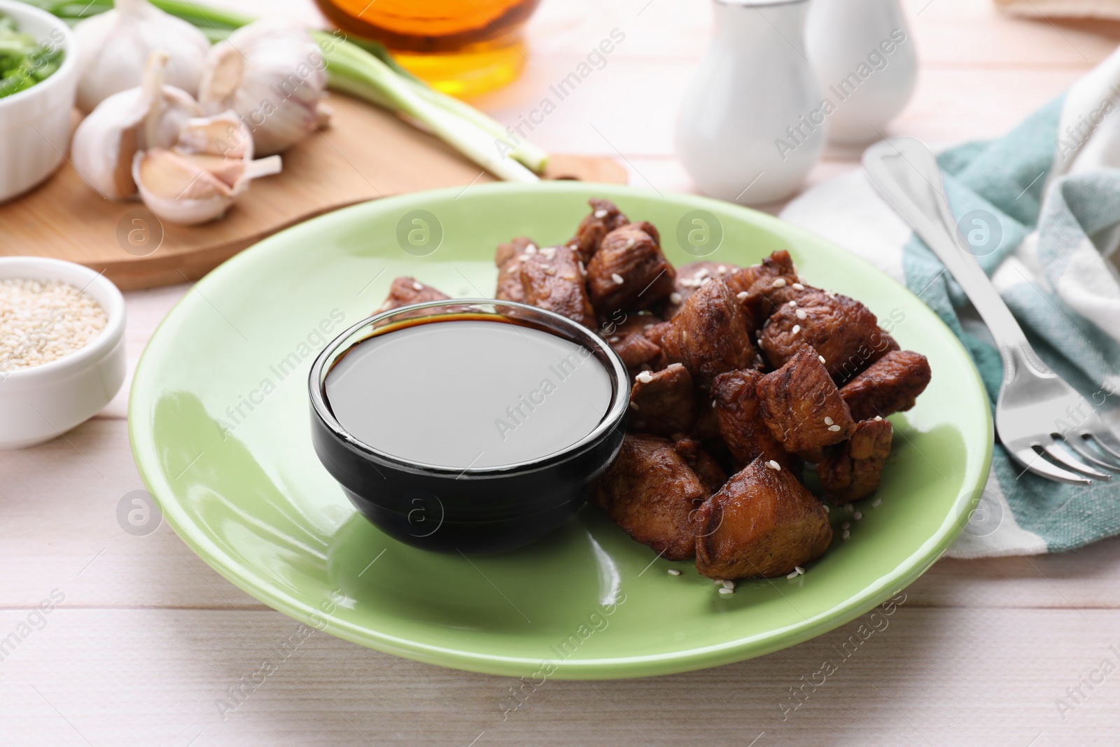 Photo of Tasty roasted meat served with soy sauce on white wooden table, closeup