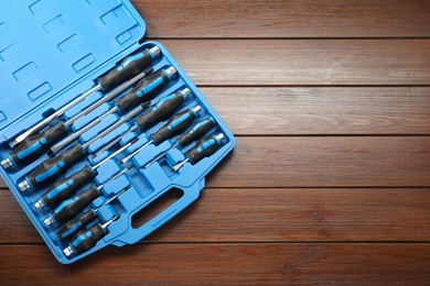 Photo of Set of screwdrivers in open toolbox on wooden table, top view. Space for text
