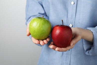Photo of Woman holding fresh ripe red and green apples on grey background, closeup
