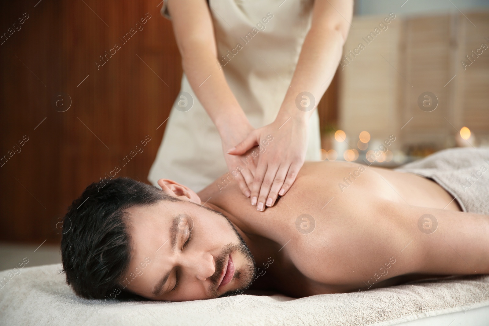 Photo of Handsome man receiving back massage in spa salon