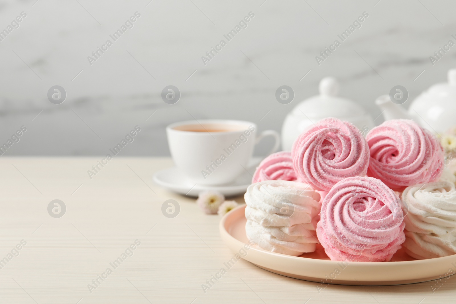Photo of Plate with delicious marshmallows on wooden table. Space for text
