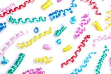 Photo of Colorful serpentine streamers on white background, top view