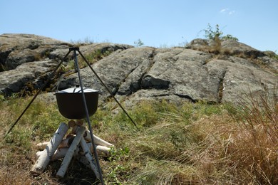Cauldron above dry firewood arranged for bonfire outdoors. Camping season