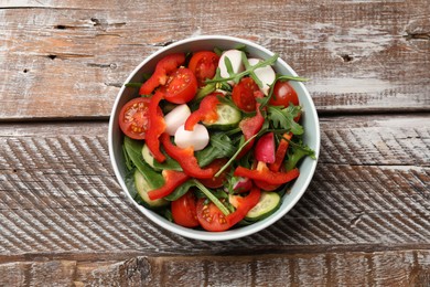 Photo of Tasty fresh vegetarian salad on wooden table, top view