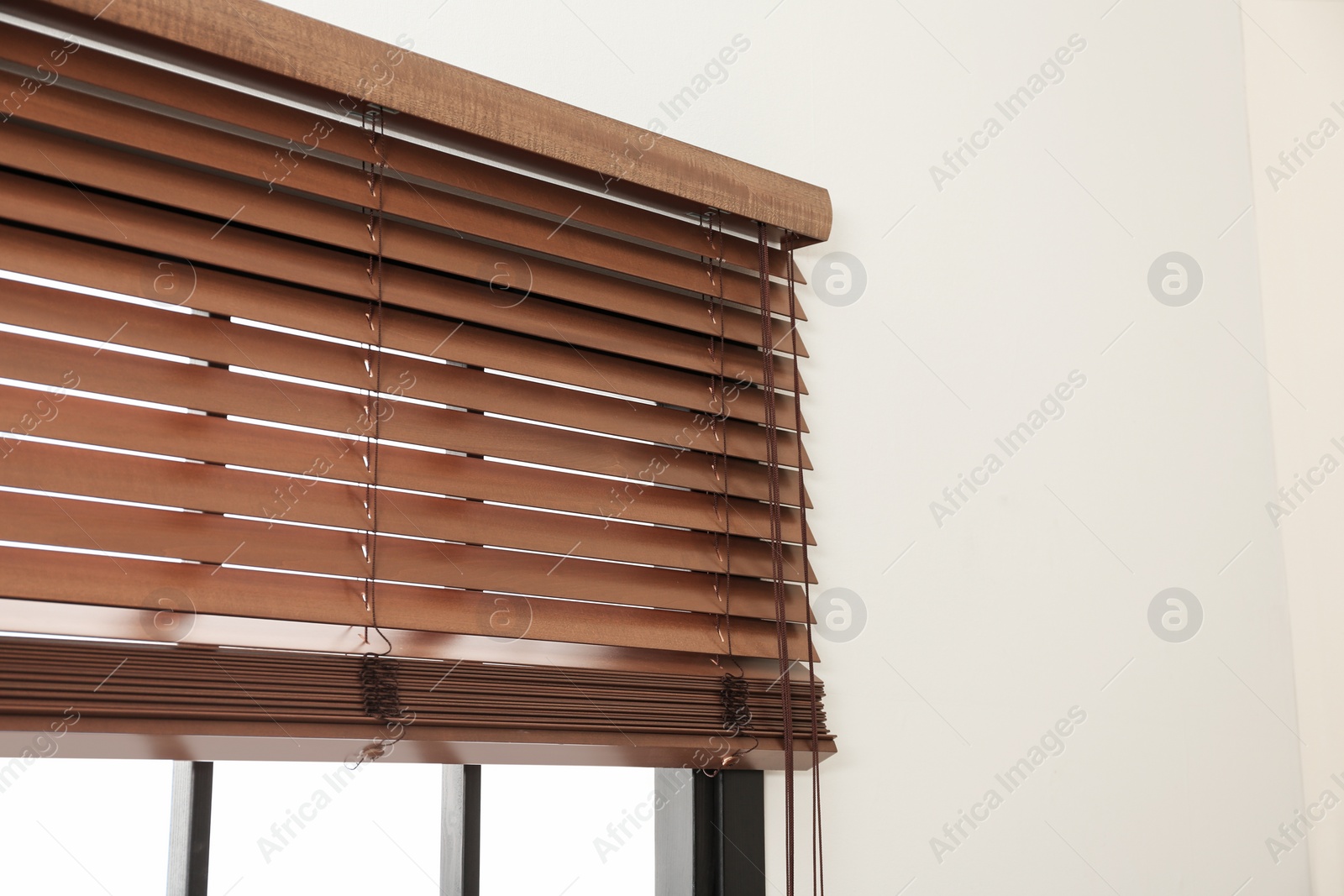 Photo of Modern window with stylish wooden blinds indoors. Space for text