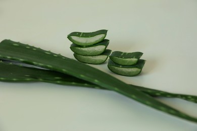Green aloe vera leaves and slices on light background, closeup