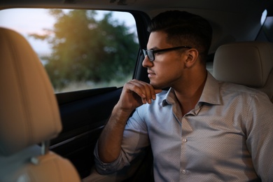 Photo of Handsome man sitting on backseat of modern car