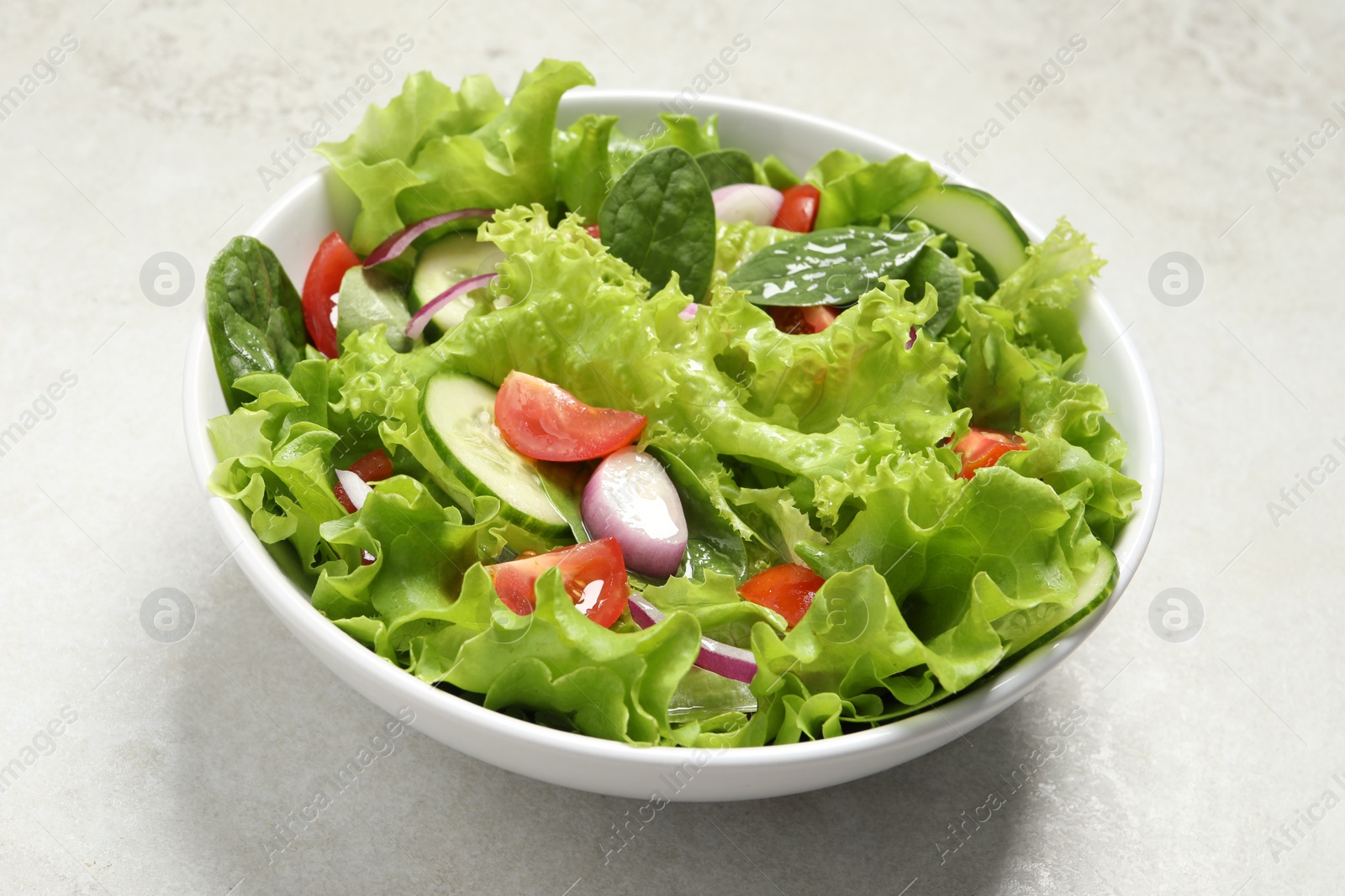Photo of Delicious salad in bowl on light grey table