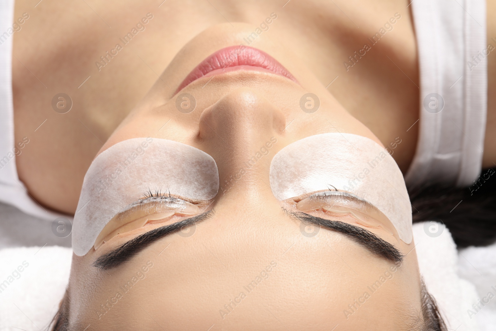 Photo of Young woman undergoing eyelash lamination, closeup. Professional service